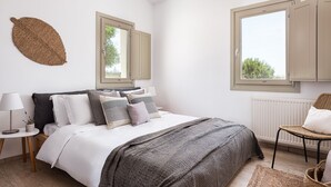 Une chambre à coucher comprenant un lit, une table de chevet, une chaise, une fenêtre et un élément décoratif fixé au mur.