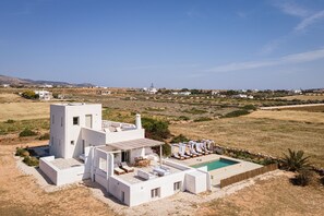 A modern white villa with a pool, outdoor seating, and a view of the surrounding landscape. - Paros House Villa - Elegant Comfort, Private Pool & Stunning Sea Sunset Views (PAROS)