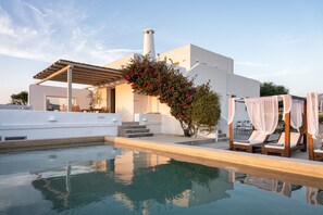A modern pool area with a clear pool, lounge chairs, and a covered seating area. - Paros House Villa - Elegant Comfort, Private Pool & Stunning Sea Sunset Views (PAROS)