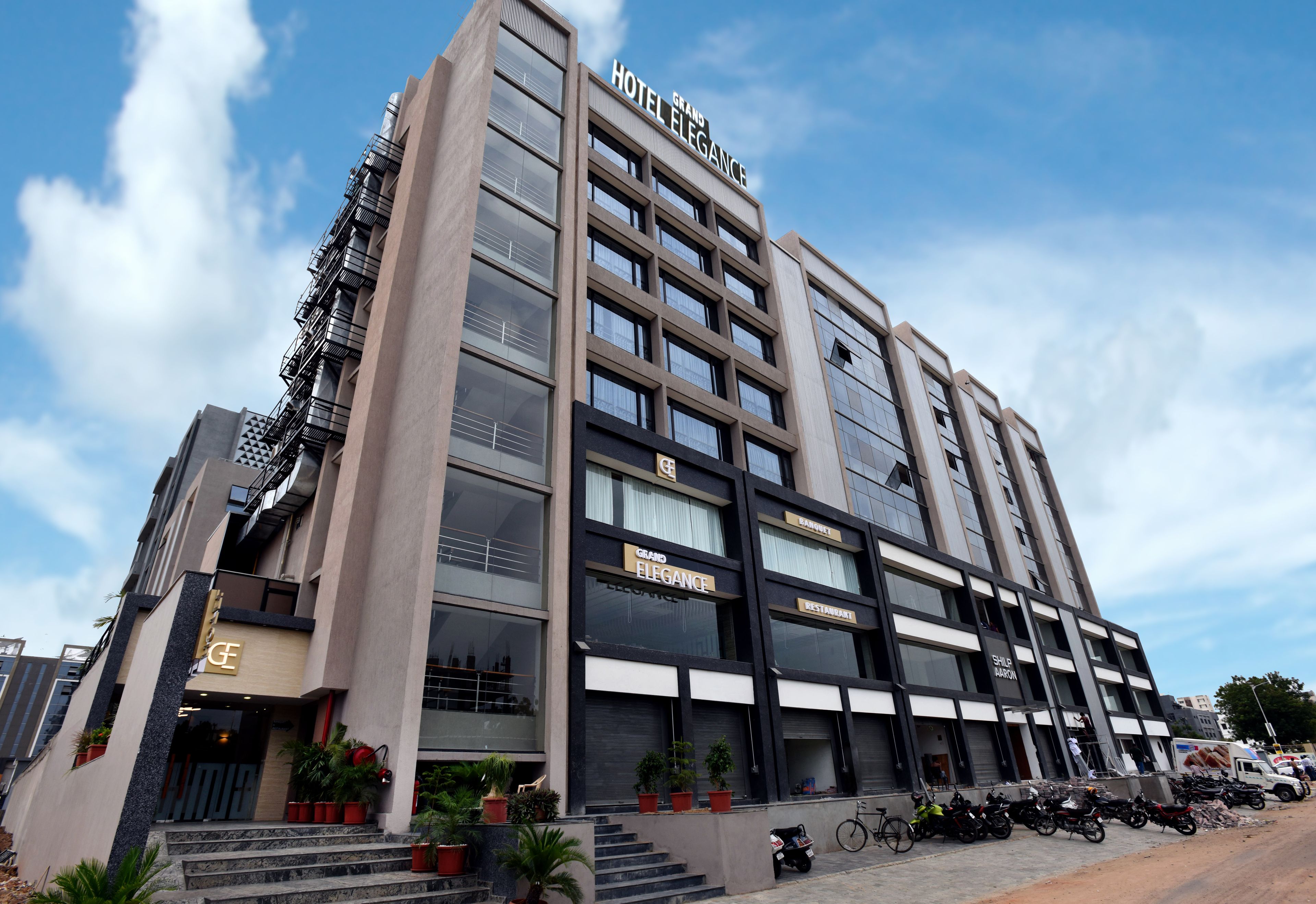 A modern hotel with multiple floors, a prominent 'Hotel Elegance' sign, and a variety of amenities including a restaurant and a shop.