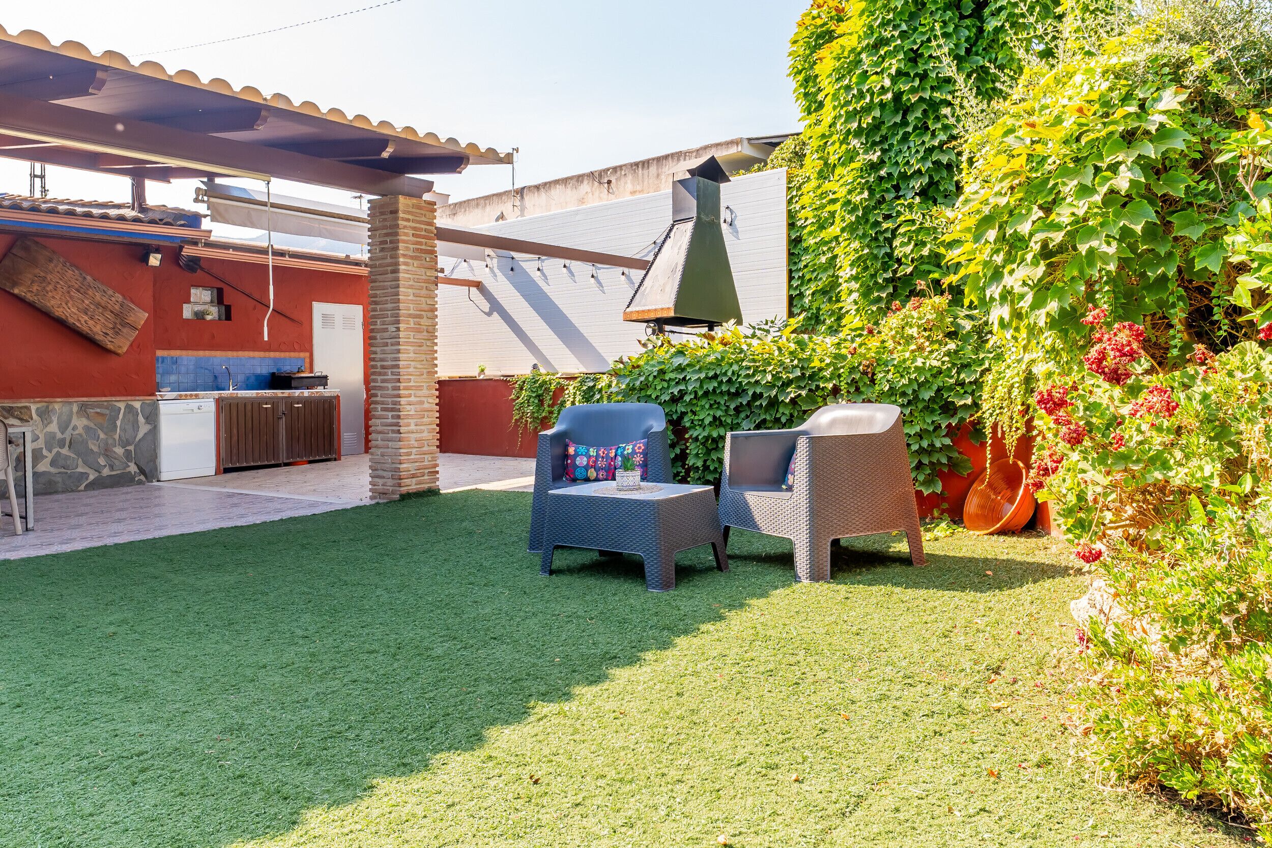 Une terrasse avec deux chaises, une table et un espace barbecue.