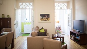 A living room with a sofa, a coffee table, a TV, and a dining area with chairs and a table.
