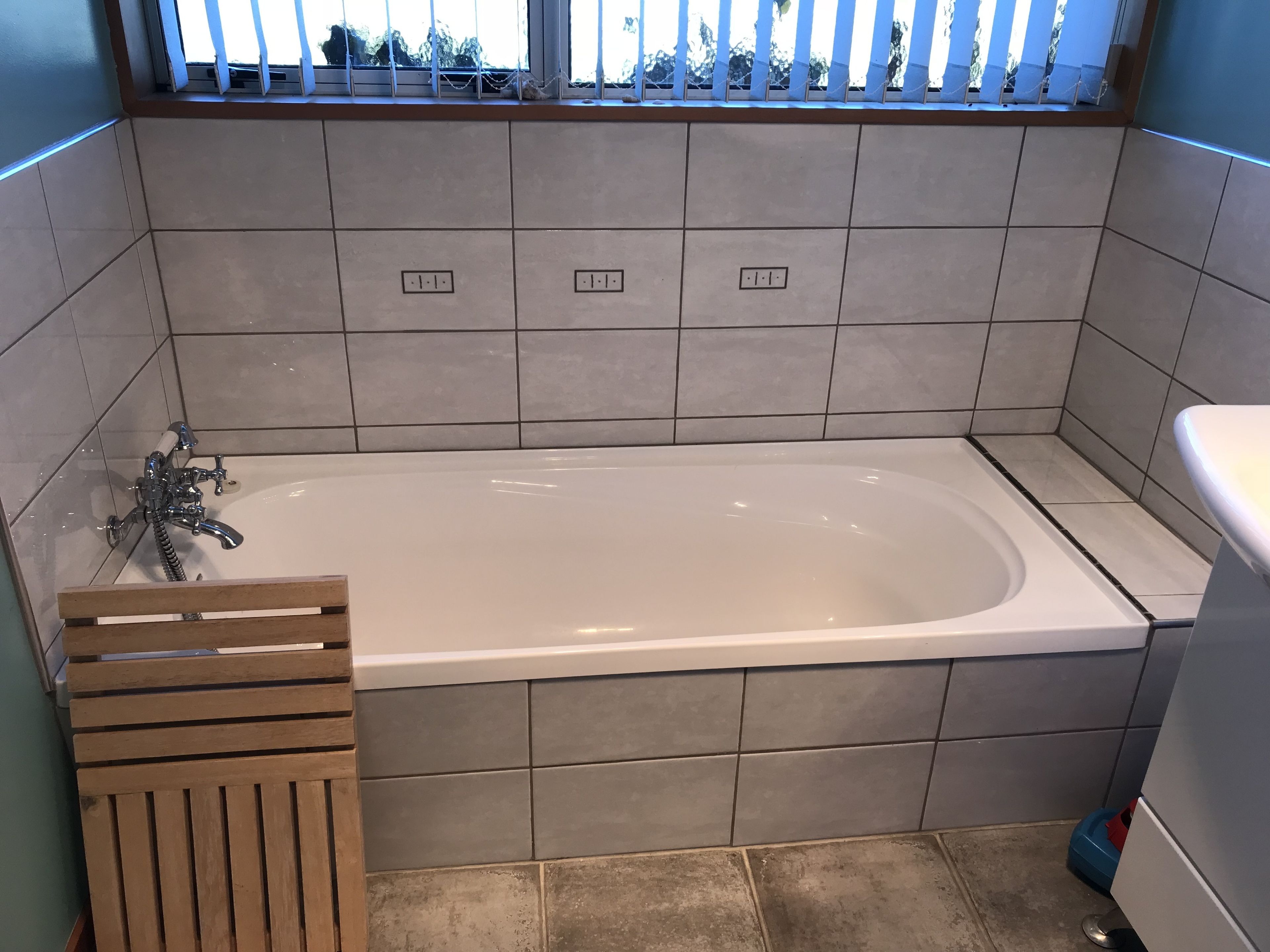A bathroom with a bathtub, a window with a view, and tiled walls.