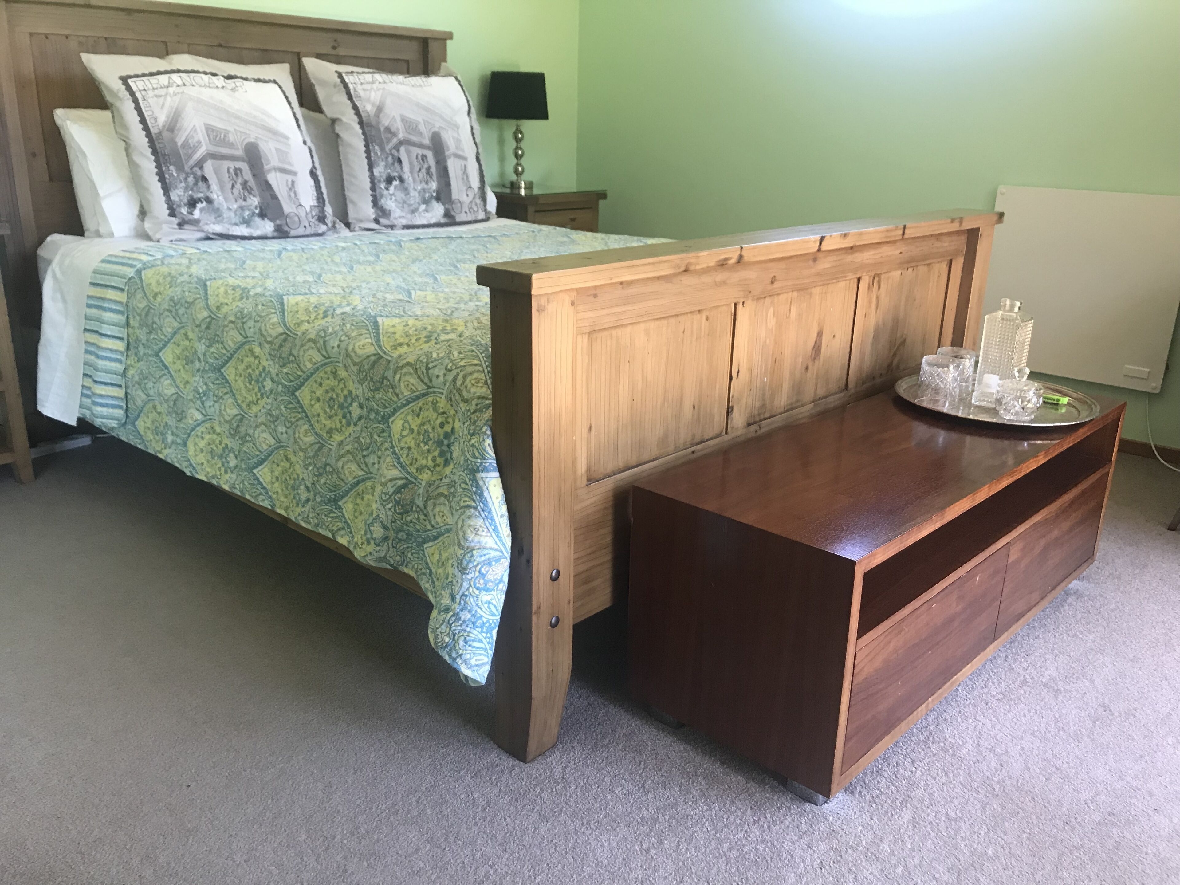 A bedroom with a bed, a wooden nightstand, a bedside table, and a lamp.