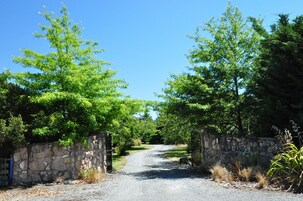 Uma estrada de cascalho leva a um muro de pedra com uma placa que diz 'NEWLANDS'.