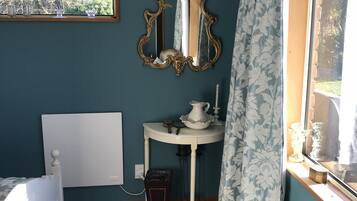Une chambre à coucher avec un lit, une table de chevet avec une lampe, un miroir et une fenêtre avec des rideaux.