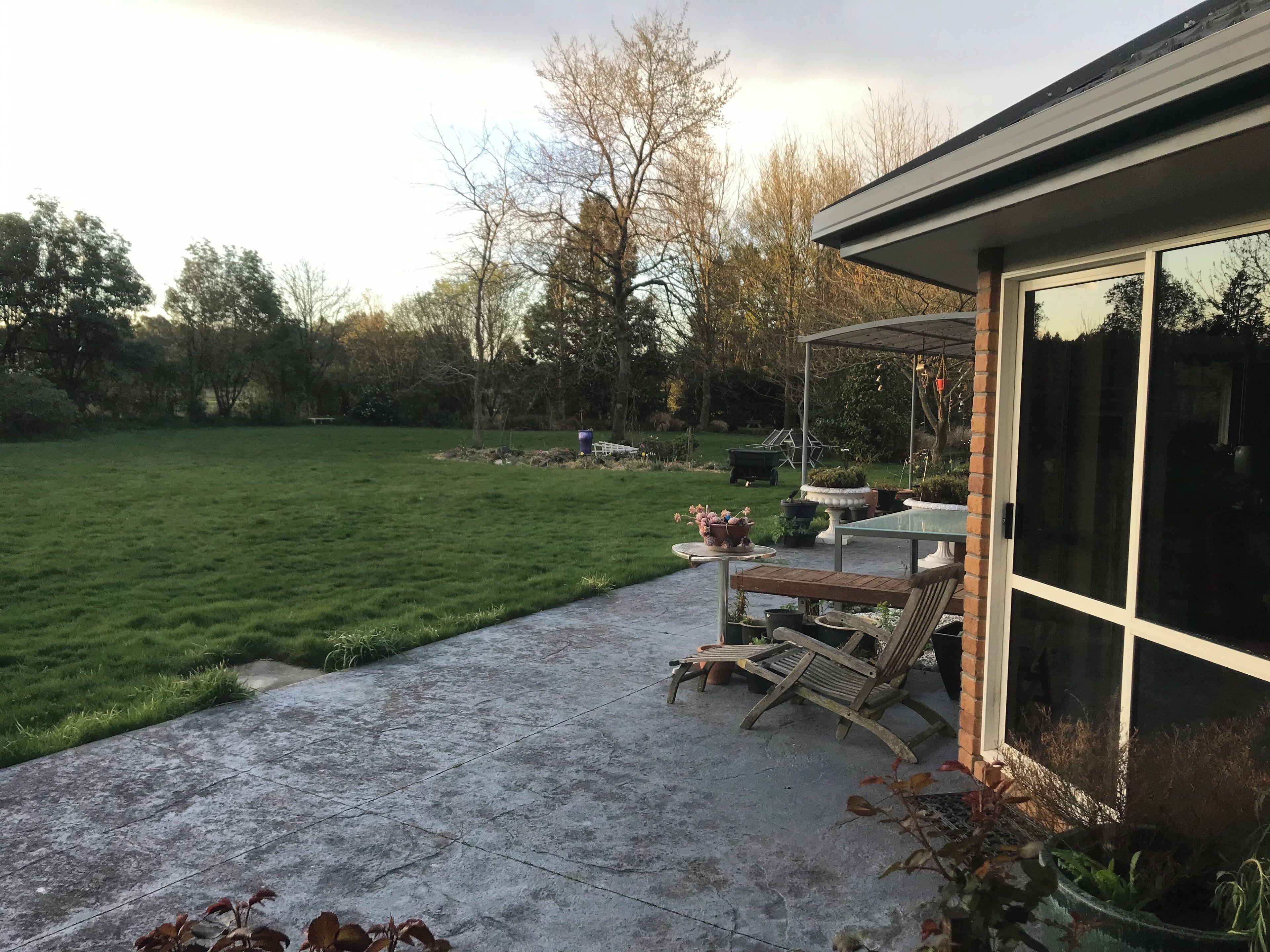 En terrasse med et bord og stole, et overdækket område og en stor glasdør.