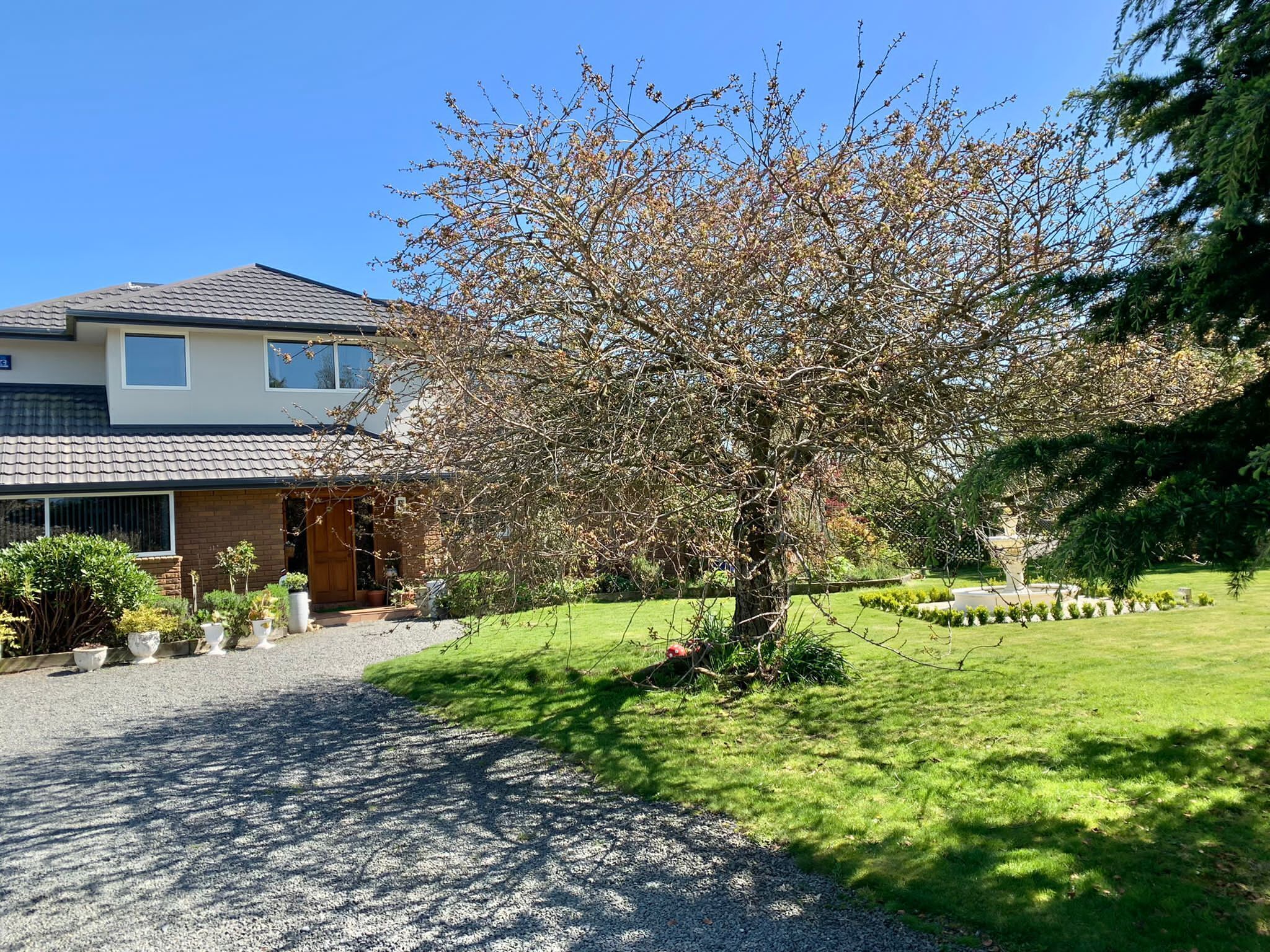 A two-story house with a gravel driveway and a well-maintained lawn.