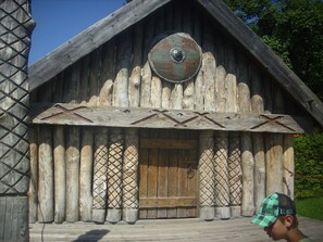 A rustic wooden building with a large circular emblem on the front, a wooden door, and a decorative lattice window.