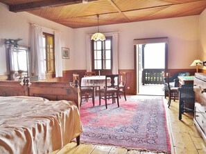 Una habitación con cama, una mesa de comedor con sillas, una araña y vistas por una ventana.