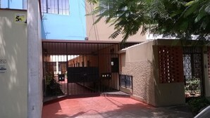 A gated entrance with a metal gate, a concrete pillar, and a building with a beige facade. - Casa Bella Lima (Lima)
