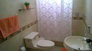 A bathroom with a toilet, sink, and shower curtain. - Casa Bella Lima (Lima)