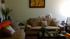 A living room with a beige sofa, a smaller sofa, a coffee table with decorative items, and a framed painting on the wall. - Casa Bella Lima (Lima)