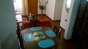 A dining area with a round table, blue placemats, and a vase with a plant. - Casa Bella Lima (Lima)