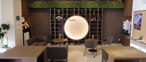 Un área de recepción con un mostrador de información, asientos y una pared verde.