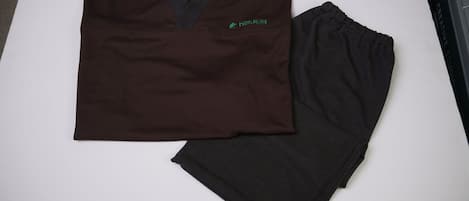 A folded dark brown shirt with a green logo and a black shirt on a white surface.