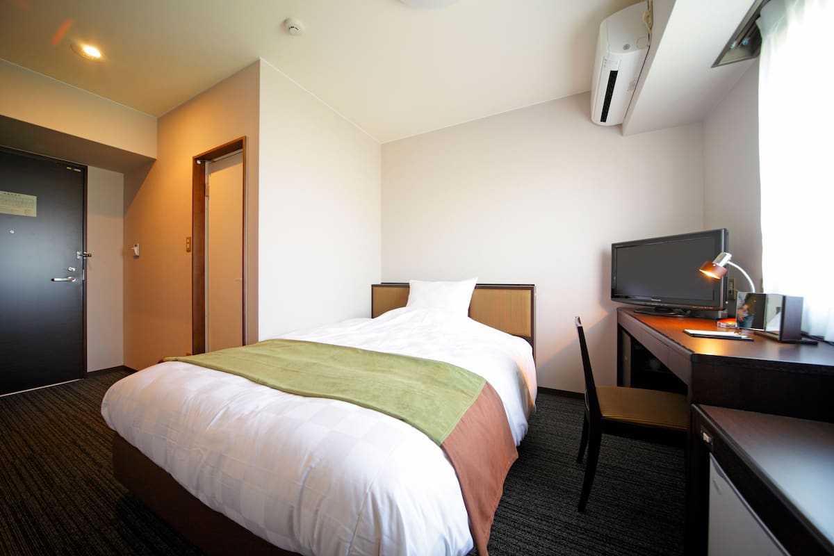 Une chambre d’hôtel équipée d’un lit, d’un bureau avec une télévision et d’un appareil de climatisation.