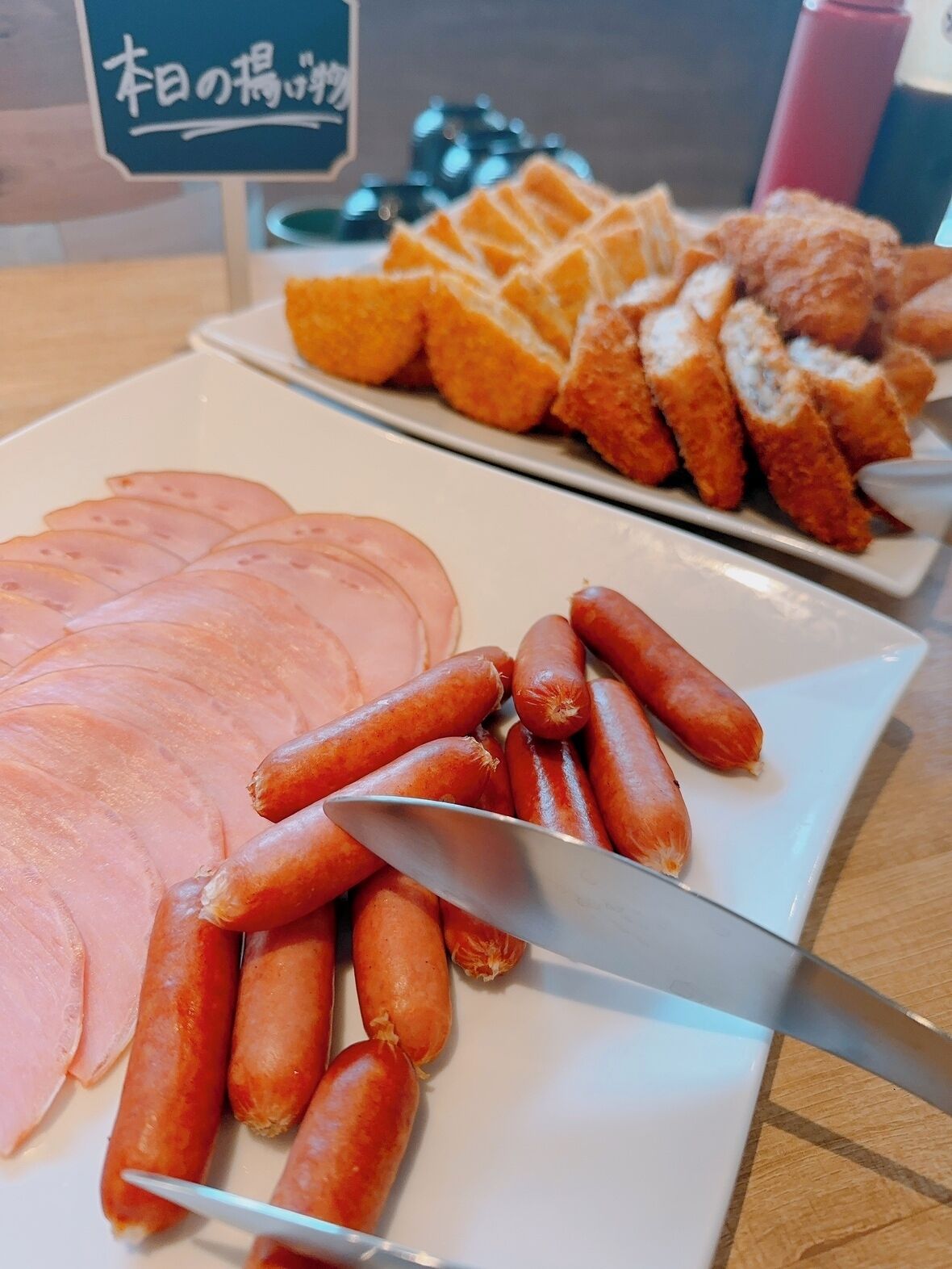 A plate with sliced ham and sausages.