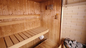 Un sauna avec des bancs en bois et un mur en briques.