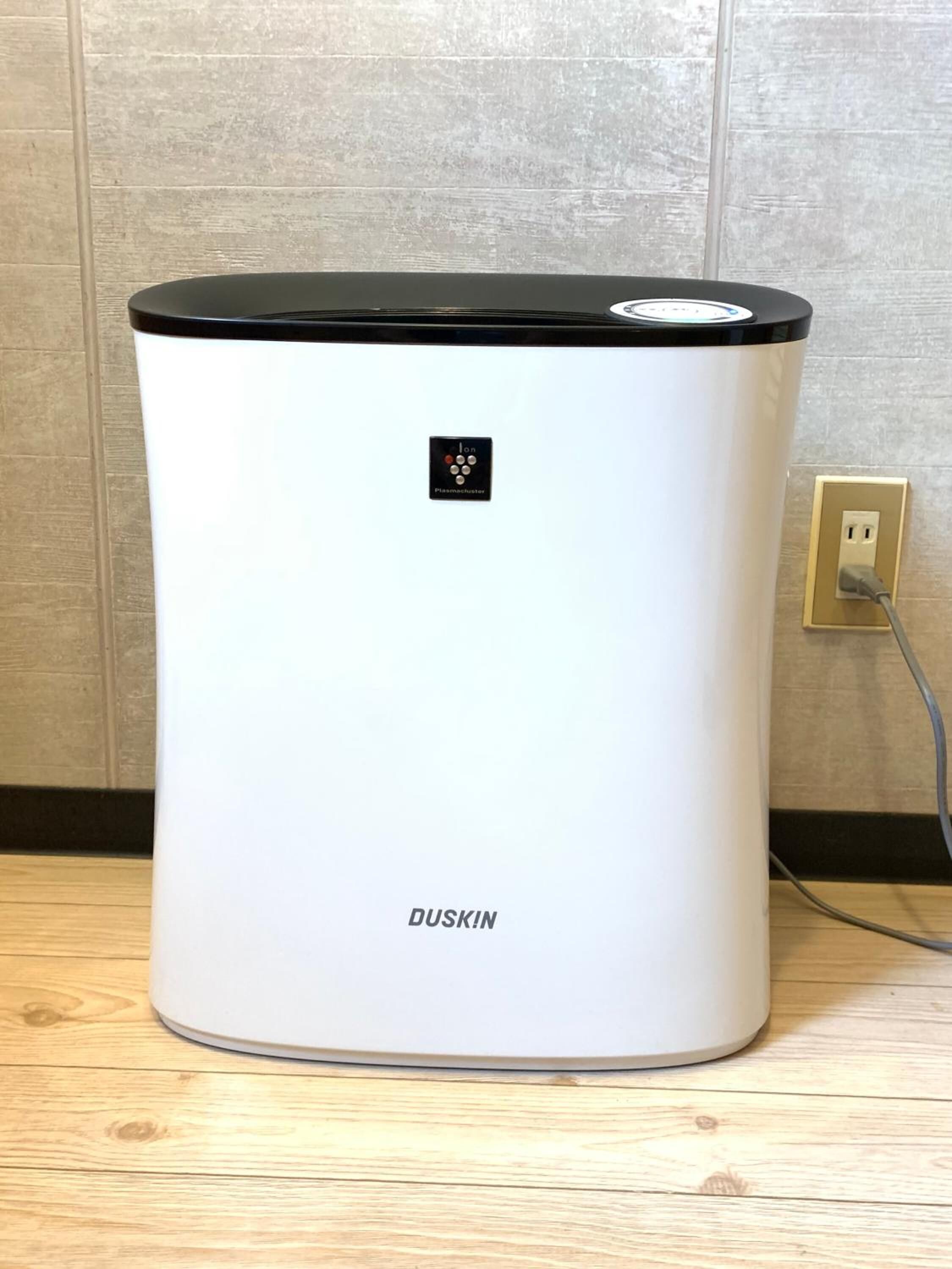 A white cylindrical device with a black top, labeled "DUSKIN," connected to a wall socket.
