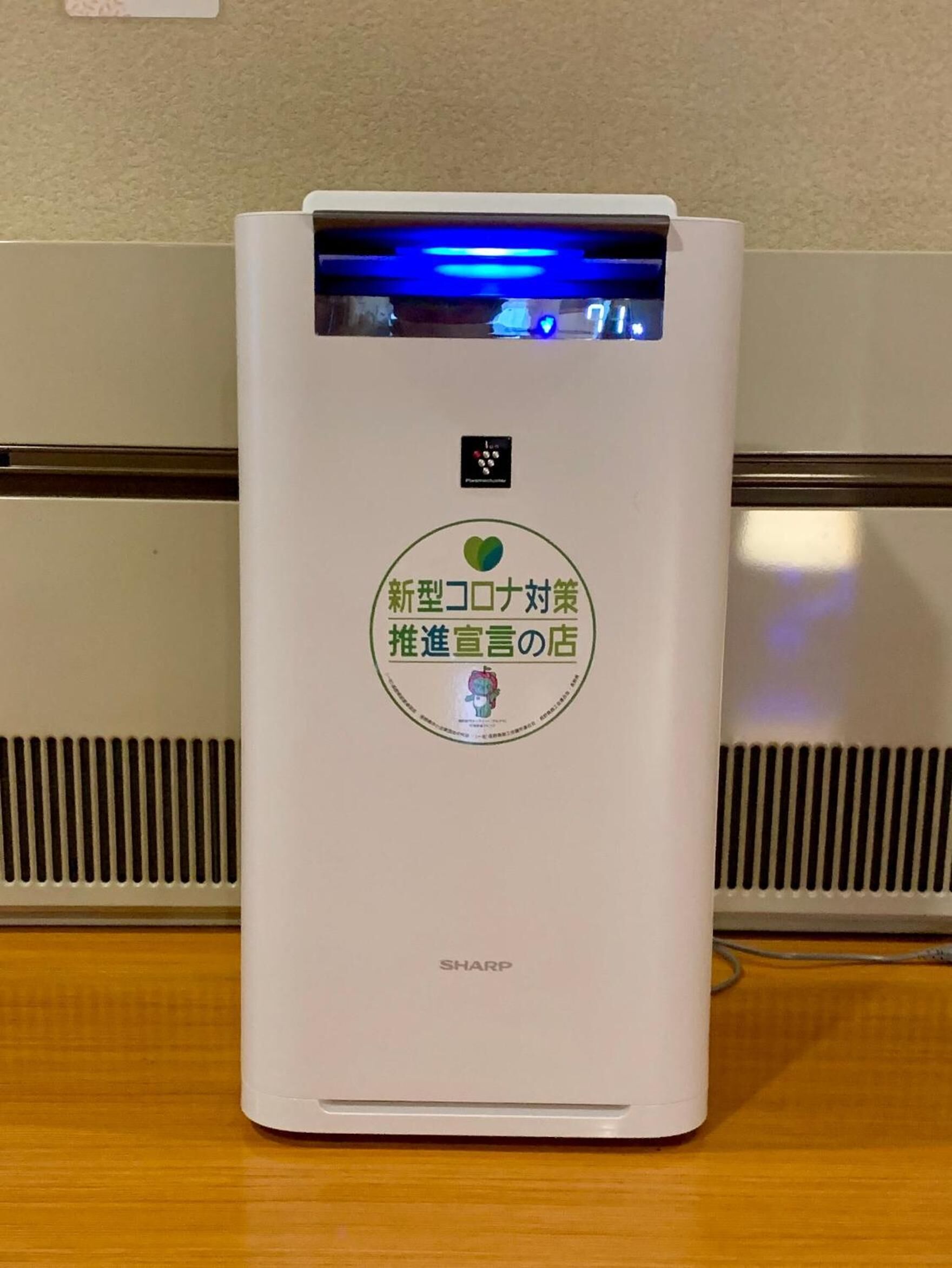 Ein weißes Luftreinigungsgerät mit digitaler Anzeige und einem Aufkleber, der es als Neuentwicklung kennzeichnet.