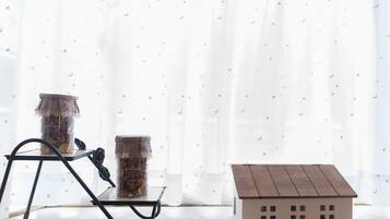 A room with a window, a small table with two jars, and a model house.