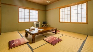 Ein traditioneller japanischer Raum mit Tatami-Boden, einem niedrigen Holztisch und Schiebetüren.