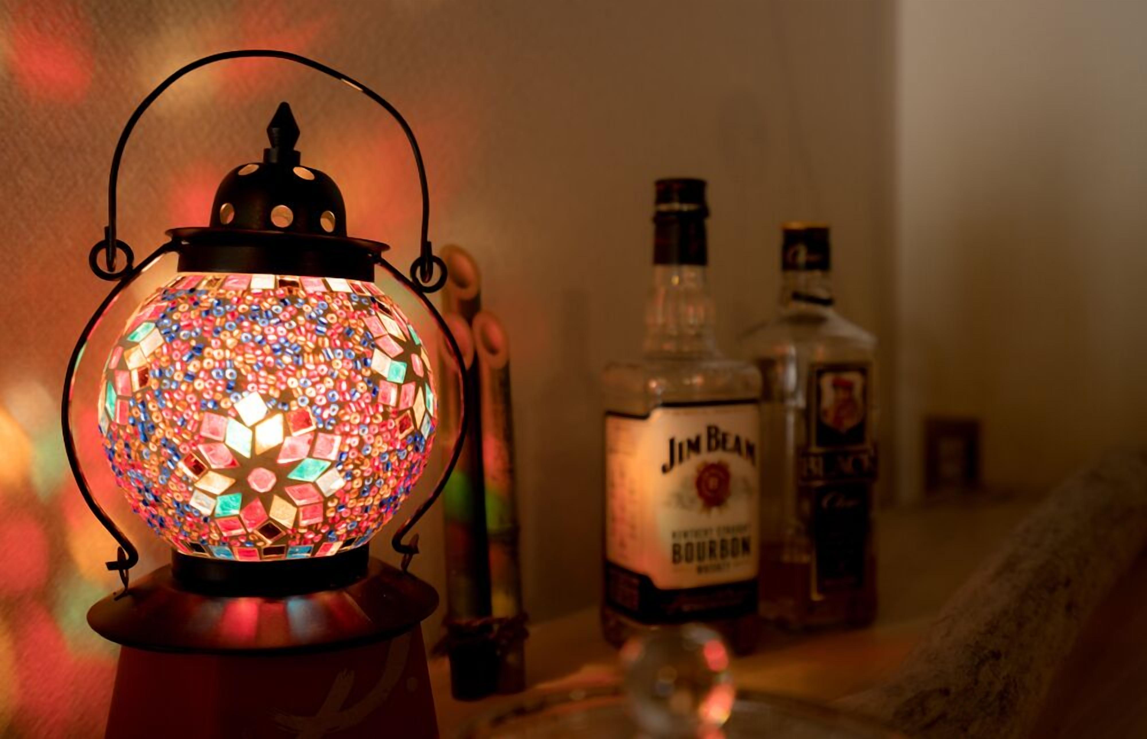 Eine dekorative Laterne mit Mosaikmuster, eine Flasche Jim Beam Bourbon und eine weitere Flasche im Hintergrund.