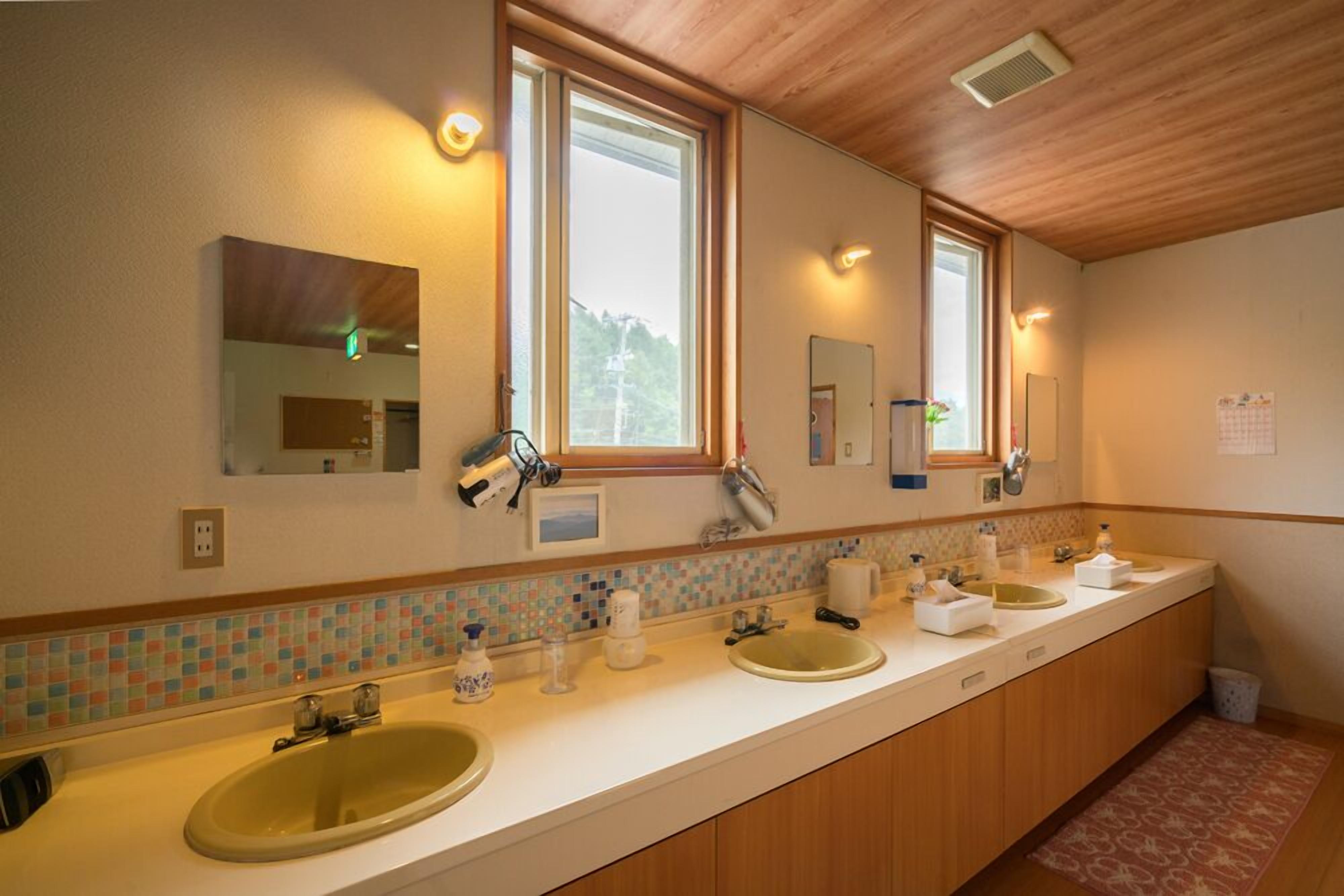 Een badkamer met een lange wastafel, twee wasbakken en een grote spiegel.