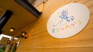 Eine Holzwand mit einem runden Schild, das eine Zeichentrickfigur und japanischen Text zeigt.