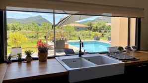 Cozinha com uma janela grande com vista para uma piscina e montanhas.