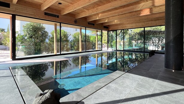 A modern indoor swimming pool with large windows and a wooden ceiling. - Charming house - Muvrinu (Calvi)