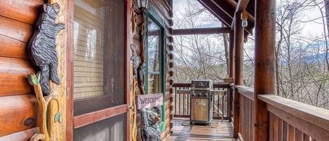 A wooden cabin with a porch, a grill, and a 'Welcome' sign.
