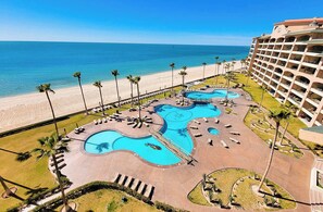 A resort with a large pool area, a beach, and a hotel building.