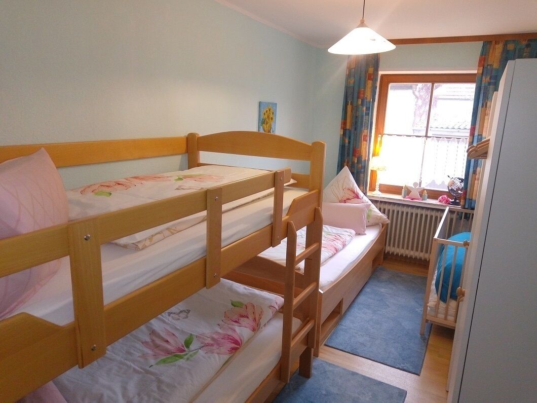 Une chambre avec un lit superposé, une fenêtre, un radiateur et un bureau avec une chaise.