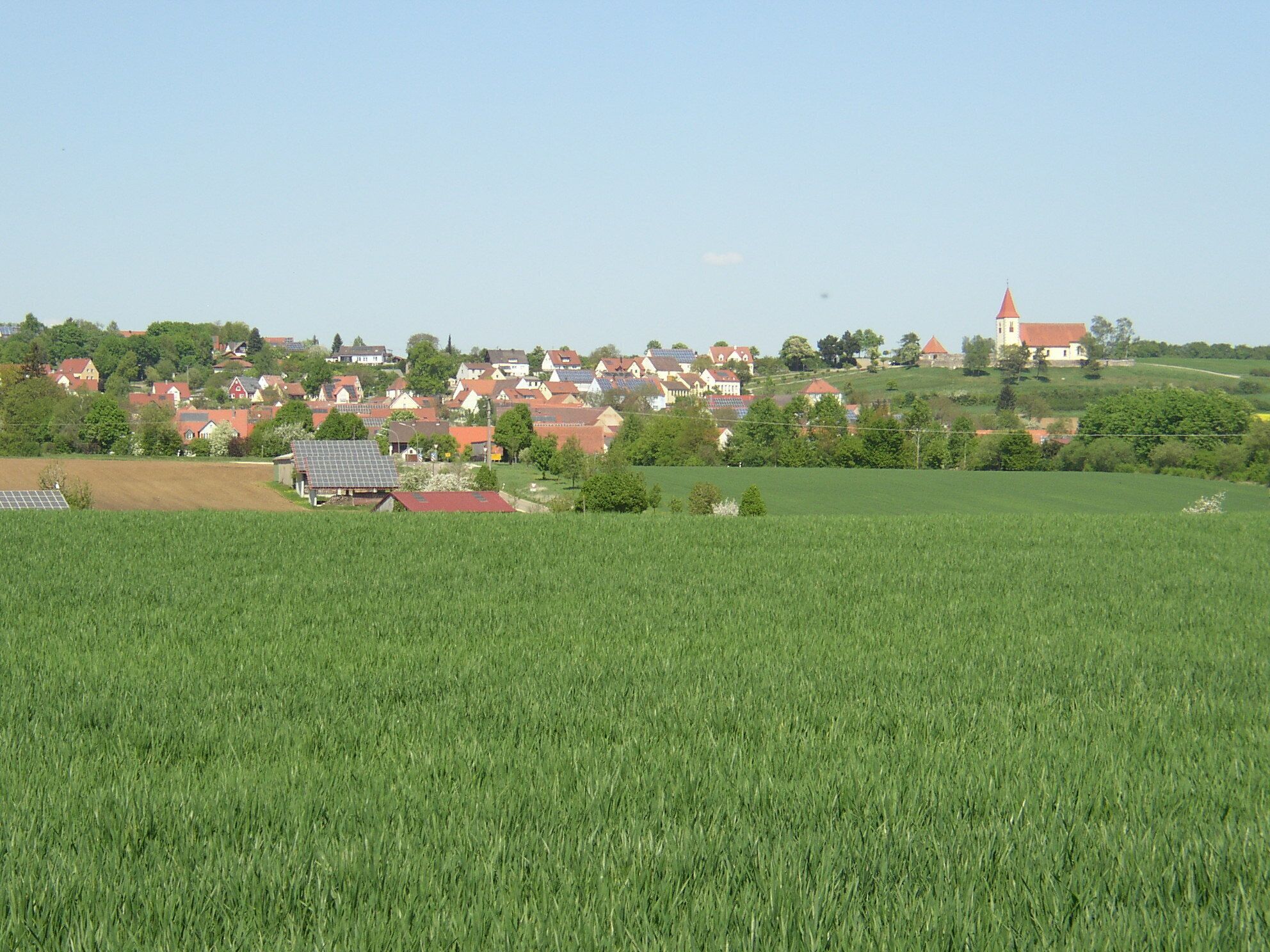 A rural village with houses, a church, and a field.
