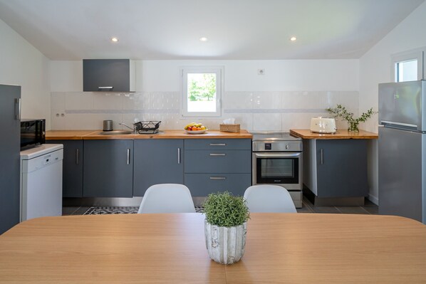 Une cuisine moderne avec des meubles gris, un plan de travail en bois et une table à manger avec des chaises.