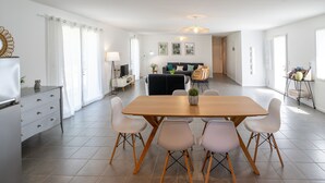 A spacious living area with a dining table, chairs, and a sofa. - Comfortable cottage in peace between sea and marsh! (Sallertaine)
