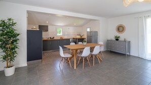 A modern kitchen with a dining area, grey tiled flooring, and a potted plant. - Comfortable cottage in peace between sea and marsh! (Sallertaine)