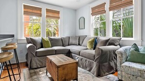 A living room with a sectional sofa, a wooden coffee table, and a bar stool. - Charleston Riviera | King Street Home - Walkable! (Charleston)