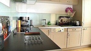 Una cucina moderna con un piano di lavoro nero, elettrodomestici in acciaio inossidabile e mobili chiari.