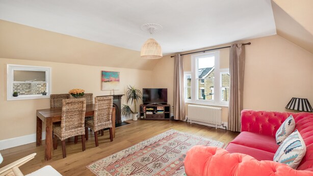 A living room with a wooden dining table, chairs, a sofa, a TV, and a large window with curtains. - Lovely 2BR, Richmond Hill & Parking (Richmond upon Thames)