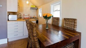 A dining area with a wooden table, wicker chairs, and a vase with flowers. - Lovely 2BR, Richmond Hill & Parking (Richmond upon Thames)