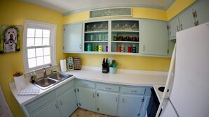 A kitchen with light blue cabinets, a white refrigerator, and a window with a view.