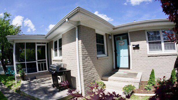A single-story house with a covered porch, a front door, and a small garden area.