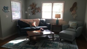A living room with a sofa, armchair, coffee table, and a rug with nautical designs.