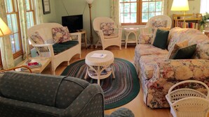 Un salon avec des meubles en osier, un téléviseur et une bibliothèque.