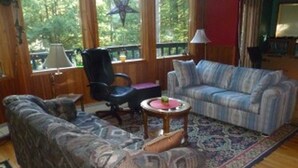 Een woonkamer met een sofa met een patroon, een gestreepte sofa, een klein rond tafeltje en een stoel.