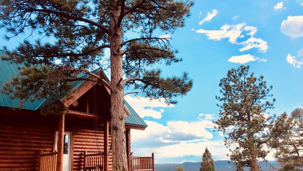 Eine Holzhütte mit Veranda, einer Bank und Blick auf Berge.