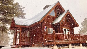 Eine Holzhütte mit Veranda und schneebedecktem Dach.